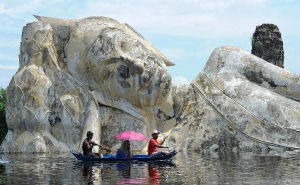 2011年10月10日，在泰國大城府，受洪災居民划船經過一尊臥佛雕像。
