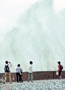 2009年10月5日下午，幾名遊客在惠安崇武古城的海堤上拍照。氣象部門提醒，風大浪高，到海邊遊玩的遊客要注意安全。 
