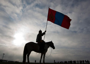 手持國旗的蒙古騎士在等待前來參加賽馬的兒童騎手們。