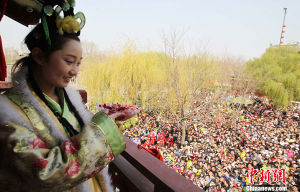 4月4日，河南開封，數千民眾圍住王員外家繡樓一睹傳說中王家小姐傾國傾城的美麗容顏，爭搶繡球做“新郎”。當日，河南開封舉行清明文化節。圖為招親後丫鬟端出喜糖鞠躬答謝觀眾。