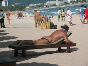 一名男性遊客幾乎全裸地曬著太陽，絲毫不避諱來往的行人