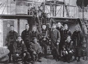 “致遠”艦部分軍官黃海海戰之前在尾樓甲板通向中部甲板的舷梯附近的合影，居中雙手交叉者為鄧世昌，其右身穿洋員軍服者是英籍輪機長余錫爾，照片中的人們可能全部犧牲在黃海海戰中.