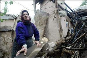 （圖）一名伊朗婦女站在地震中被毀的房屋前