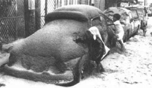 沒有戴口罩的孩子們在被厚厚的火山灰塵覆蓋的汽車旁玩耍