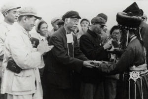 1952年8月，內蒙古自治區各族民眾在途中迎接中央東北內蒙古訪問團。圖為訪問團團長彭澤民（前排左二）、副團長薩空了（前排左一）等同志，接過蒙古族婦女敬獻的馬奶酒
