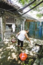 一老人在朱彝尊故居院子裡洗衣服