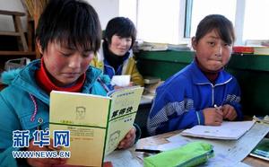 寧夏西吉縣三合村三合中學七年級4班學生張鳳兒(左)在翻看好心人寄來的輔導書(11月8日攝)。