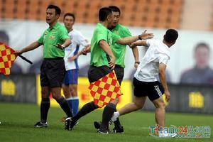 青島球迷衝進場地欲打裁判。助理裁判攔住球迷。