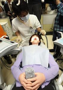 3月25日，在日本東京昭和大學，一名牙醫正在對新型牙科訓練機器人（下）進行“治療”。