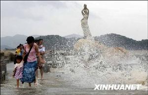 8月4日，在廣東珠海漁女雕塑前的棧橋上，遊客躲避被大風掀起的海浪