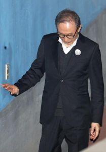 李明博被獄警攙扶進法院，無精打采