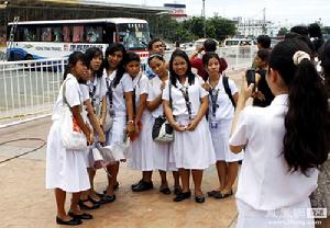 一群菲律賓女學生在事發現場以曾被劫持的香港旅遊大巴為背景合影留念。
