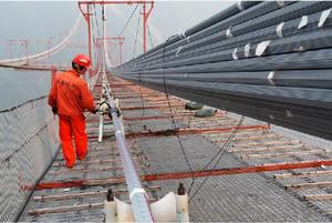 2010年10月20日，工人在“貓道”上查看正在安裝的最後一根索股。矮寨特大懸索橋有兩根主纜，主纜直徑855毫米，長1600餘米，重量為6千噸。每根主纜由169根索股構成，每根索股又由127根直徑5.25毫米的平行高強鍍鋅鋼絲組成，每根主纜包含21463根鋼絲，每根高強鋼絲的強度均大於1670兆帕，每根主纜能承受超過3萬噸的拉力荷載。