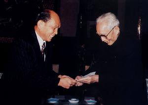 （圖）1986年11月29日，首任理事長王震接受香港中華總商會會長霍英東捐款500萬元港幣