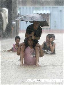 2009年7月17日，在菲律賓首都馬尼拉郊外，當地居民在齊腰深的洪水中行進。
