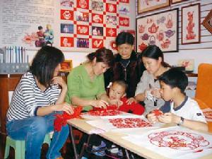 （圖）張崢嶸(左二)、張麗群(右二)指導小朋友學習剪紙