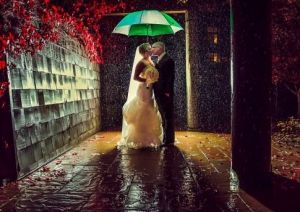 新郎在雨中撐起綠白相間的雨傘擁吻新娘，雨滴落在新人周圍，令這一場景更加溫情。