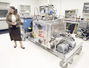 蘭利研究中心材料工程師卡倫·塔米戈站在電子束無模成形製造器(EBF3)模型旁邊