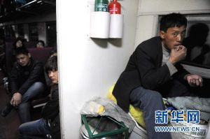 L160次列車上，一位沒有座位的乘客坐在自己的行李上休息（1月20日攝）。新華社記者 郭晨 攝