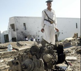 爆炸現場，一名埃及保全人員站在被炸毀的汽車的殘骸旁