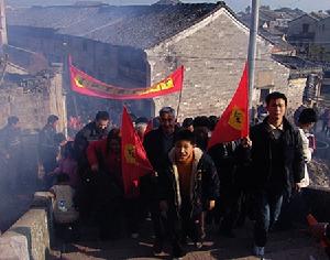 終於到了廟門，鞭炮噼叭地響起，淡藍的煙霧中，送祭的人們更加莊重