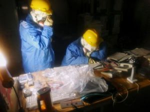 福島第一核電站第一和第二機在地震中嚴重損毀，周三清晨，堅守在此的工人們正仔細檢查中央控制室的數據，試圖找到故障點。他們的臉龐由於呼吸面罩的遮擋而無法看清。