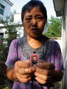 8月24日，鮎魚山鄉平塘村村民鮑祥義的妻子，展示丈夫遺照。