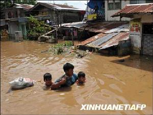 10月31日，受颱風影響，在菲律賓內湖省的聖克魯斯鎮，一名男子帶著孩子在被洪水淹沒的街道上行走。