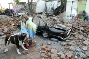 一位婦女在震後的廢墟前面