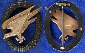 Juncker空軍傘兵章早期銅鋅合金（tombak）材質，保存的非常完美。圓頂鉚釘、別扣組合都是高品質的。鷹飾的鍍金厚重均勻，樹葉飾環化學氧化變黑，凸起部分略微被磨亮。廠商的LDO代碼：C.E.   Juncker,Berlin SW被清晰深深砸印鷹飾物背面。C.E. Juncker早期空軍傘兵章各種細節參數典型的範例。