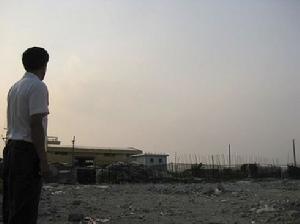 何瑞超站在兩棟未拆的建築物前，一臉無奈