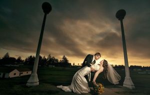新郎在暴風雨來臨之前擁抱著新娘。新娘手中的向日葵花束與陰暗的天氣形成鮮明對比。